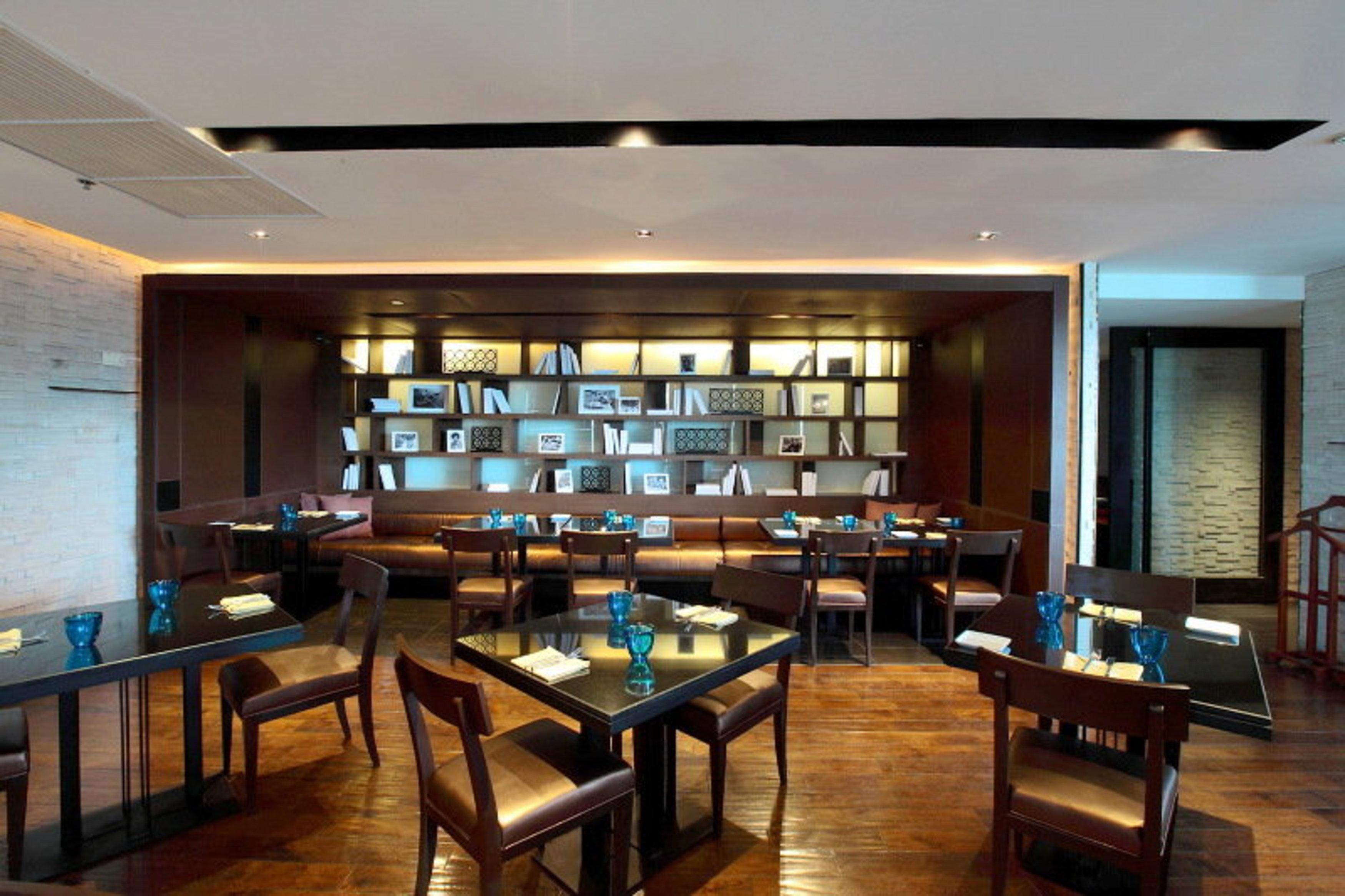 Pathumwan Princess Hotel - Sha Extra Plus Certified Banguecoque Exterior foto The photo depicts a modern restaurant interior. It features a warm and inviting atmosphere with wooden flooring and soft lighting. The restaurant has several tables arranged for dining, each set with blue glassware and white napkins. 

On one side, t