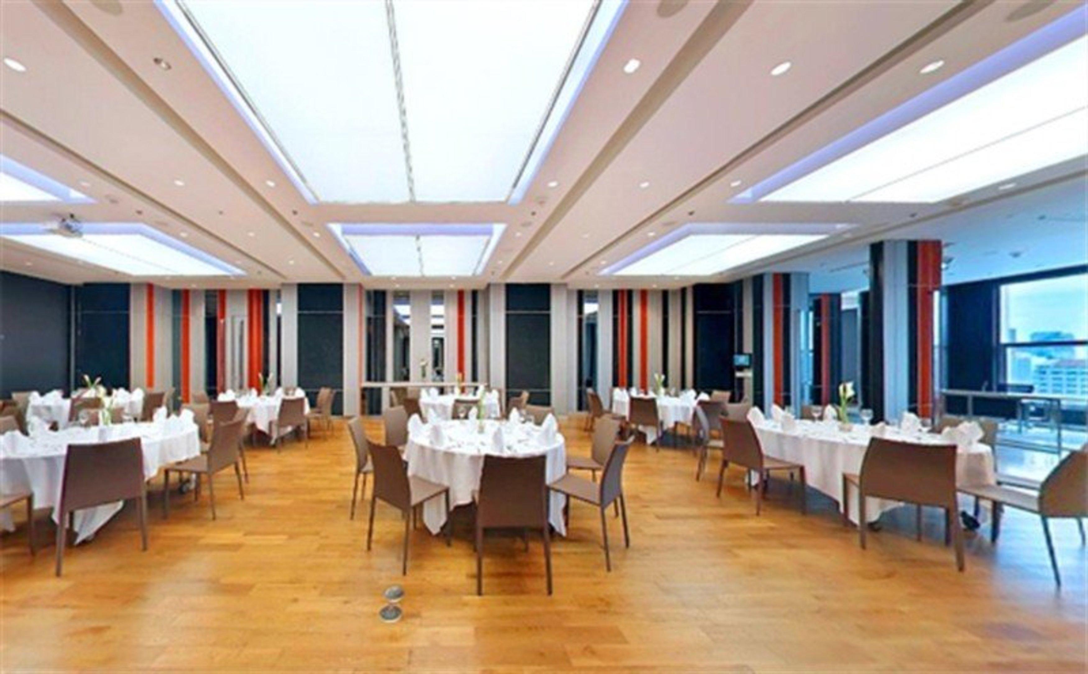 Pathumwan Princess Hotel - Sha Extra Plus Certified Banguecoque Exterior foto The image shows a spacious restaurant or dining area. The floor is made of wooden planks, and the room features several tables, each covered with a white tablecloth and set for dining. The seating consists of modern chairs arranged around the tables.