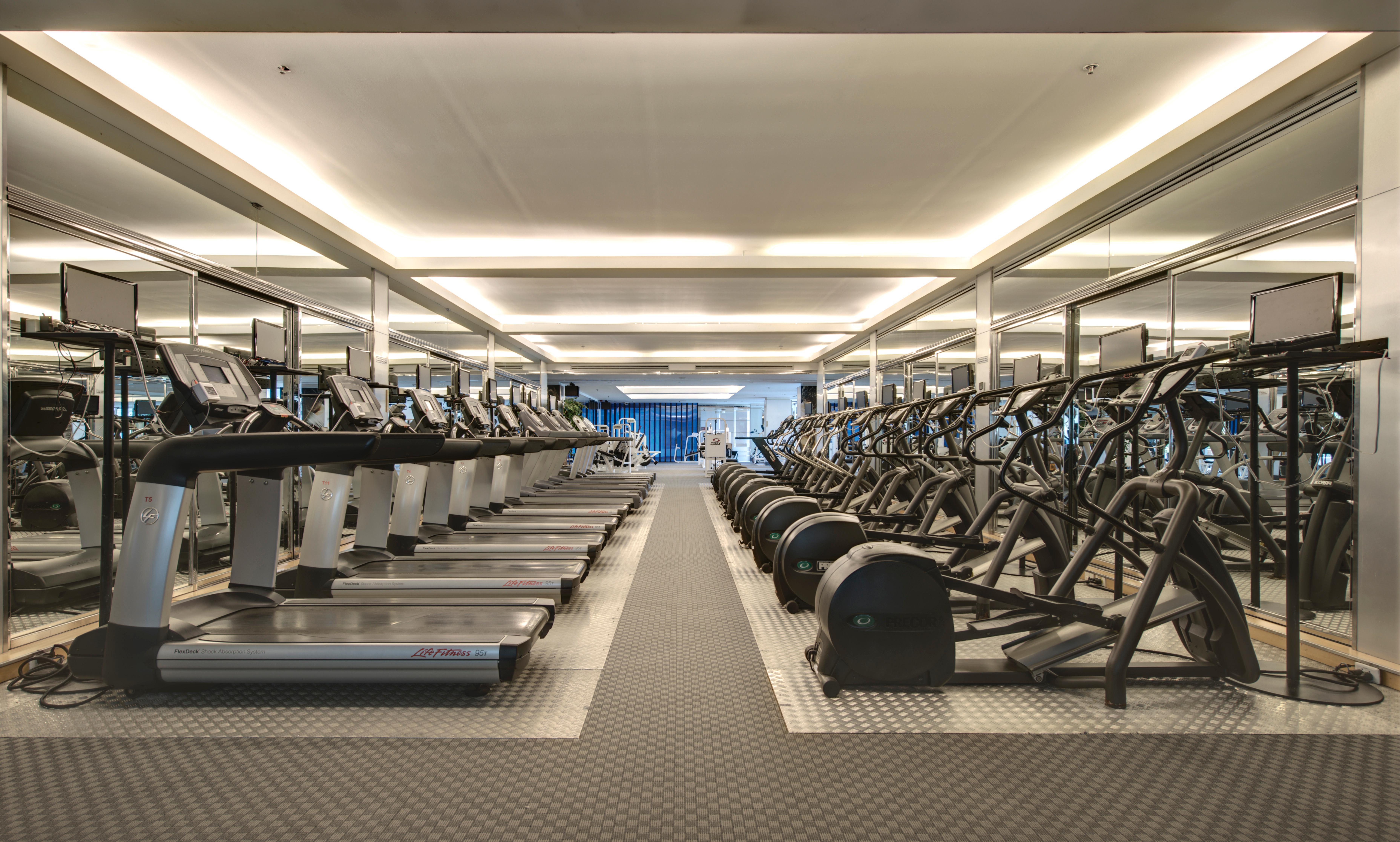Pathumwan Princess Hotel - Sha Extra Plus Certified Banguecoque Exterior foto The photo shows a modern gym space featuring rows of exercise equipment. On one side, there are several treadmills and possibly elliptical machines lined up. The other side has stationary bikes and strength training equipment, arranged neatly. The gy