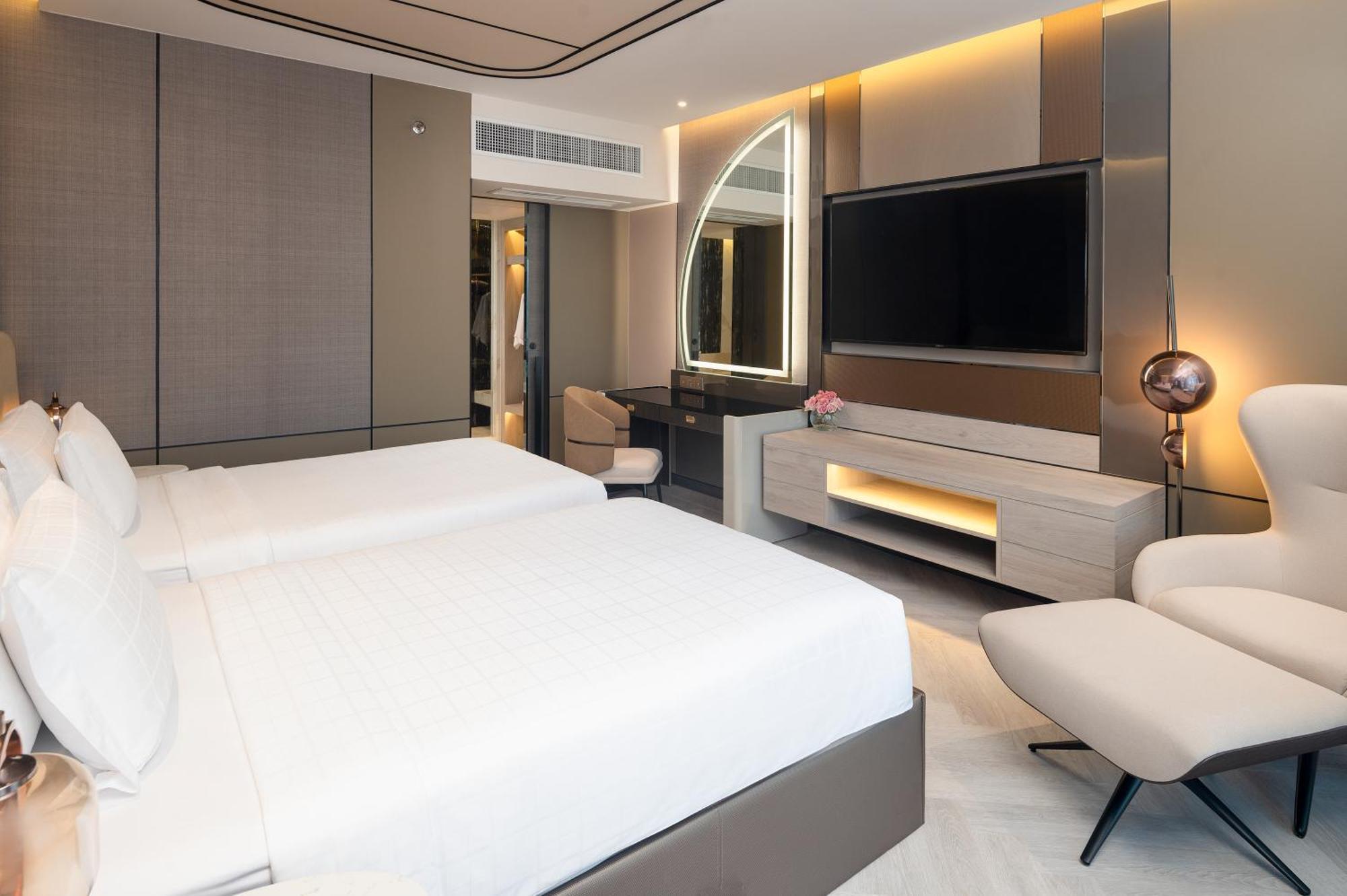 Pathumwan Princess Hotel - Sha Extra Plus Certified Banguecoque Exterior foto The photo shows a modern hotel room featuring two beds with white bedding. The room has a sleek design with a combination of neutral colors and stylish lighting. There's a large flat-screen TV mounted on the wall, a work desk with a chair, and a comf