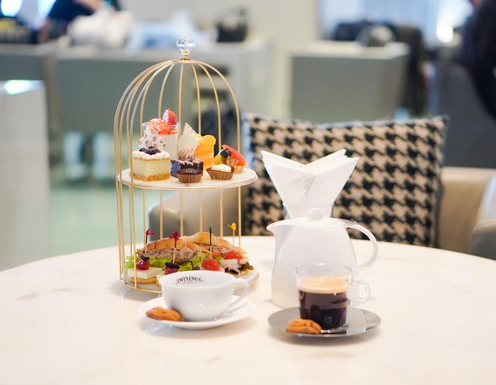 Pathumwan Princess Hotel - Sha Extra Plus Certified Banguecoque Exterior foto The photo shows a beautifully arranged afternoon tea setting. At the center, there is a golden birdcage stand filled with an assortment of desserts, including pastries and small cakes, garnished with fruits. In front of the stand, there is a white te
