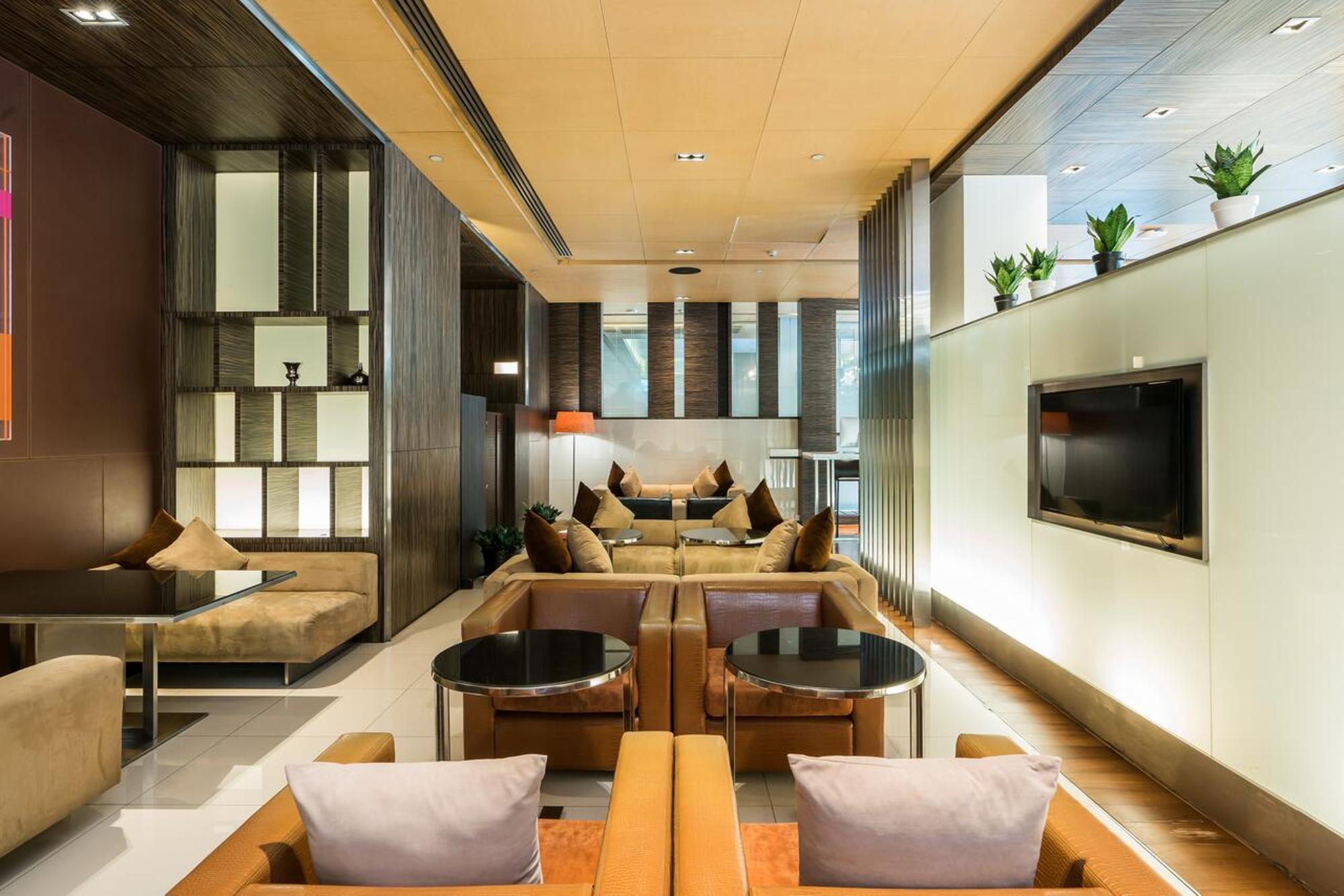 Pathumwan Princess Hotel - Sha Extra Plus Certified Banguecoque Quarto foto The photo shows a modern lounge area characterized by a sleek and contemporary design. The space features multiple seating arrangements with comfortable sofas and chairs, paired with stylish coffee tables. Soft lighting creates a warm atmosphere, and
